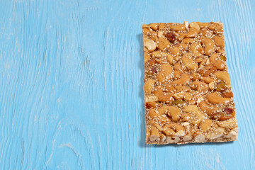 Cashew nuts, peanuts and sesame seeds bar with honey on a light blue wooden background with copy space