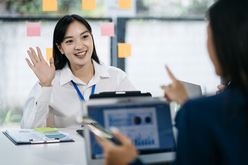 Asian manager mentor talking to young Asian coworker, showing online project results at meeting.