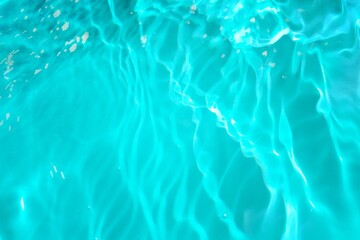 Defocus blurred transparent blue colored clear calm water surface texture with splashes reflection. Trendy abstract nature background. Water waves in sunlight with copy space. Blue watercolor shine.