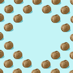 Pattern made of raw walnuts with copy space on bright blue background. Food concept.