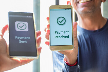 Cropped image of a smiling South Asian man showing a message of successful payment from his friend. Instant digital money transfer or real time payment concept. 