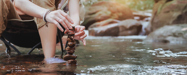 Close-up Hand of woman to build natural stone arrangements, Balance stones in the stream, Trying...