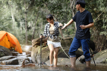 Asian Teenagers walk in the natural stream with a camping tent in the background, Enjoying the...