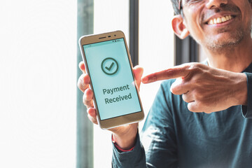 Cropped image of a smiling South Asian man pointing out the notification payment received on his smartphone. Instant money transfer or real time payment concept. - obrazy, fototapety, plakaty