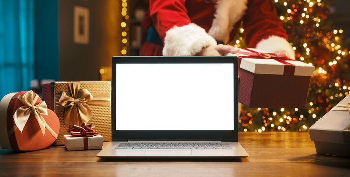 Santa Claus bringing a gift and blank laptop