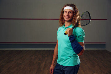 Portrait of male squash player standing with racket ready for game