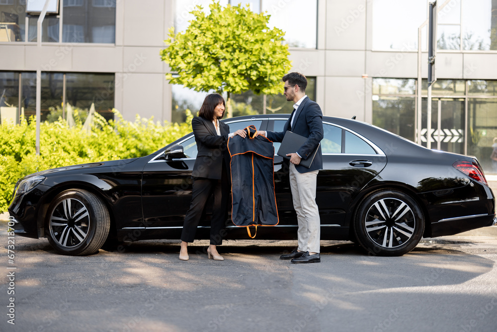 Wall mural female chauffeur gives a businessman his suit, after a business trip in luxury taxi. concept of pers