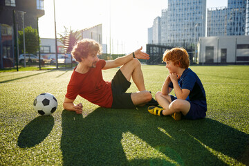 Dad and son having nice conversation after football training recreation activity