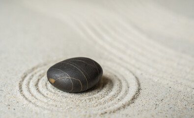 Black zen stone on sand round ripple