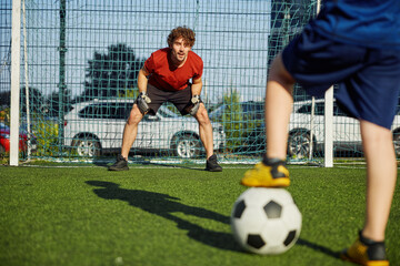Father goal keeper and boy son forward training football at stadium