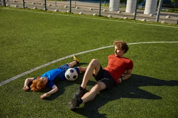 Foto op Plexiglas Tired father and son soccer player lying on grass of football field © Nomad_Soul