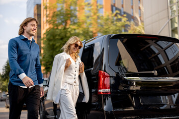 Business people get out of a minivan taxi, during a business trip by car. Concept of business trips and transportation - 673215975