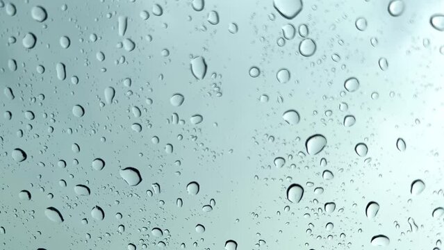 Raindrop on white transparent mirror in rainy day. Falling rain from rainy season sky background. Slow motion footage.