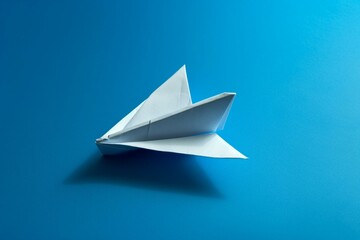 Concept of innovation and inspiration. A folded paper plane casting a shadow against a blue backdrop. Generative AI - obrazy, fototapety, plakaty