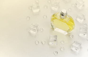 Female perfume yellow bottle, Objective photograph of perfume bottle in ice cubes and water on white table. View from above. Mockup product photo, concept of freshness and aroma