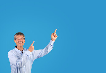 Excited businessman in shirt pointing to blank space aside, studio