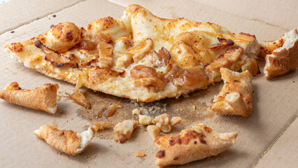 Leftover pizza and pizza crust on a take-out box..  close up of pizza pieces and junk food remains...