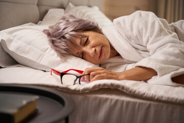 Woman is dozing in a bright bedroom on soft pillows