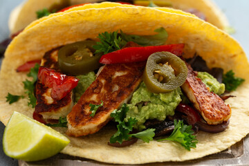 Fried halloumi fajitas with pan roasted onions and bell peppers, avocado guacamole and pickled jalapeno peppers