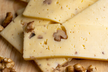 Sliced piece of milk cheese with walnuts