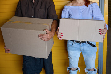 Female and male are standing near a yellow container
