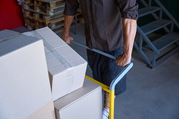 Man with strong arms is carrying a lot of boxes