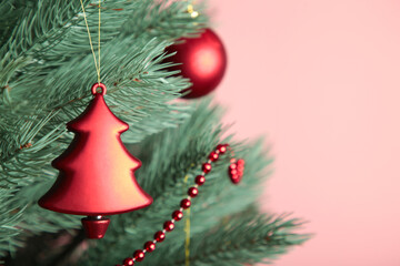 Christmas tree with red decor on pink background.