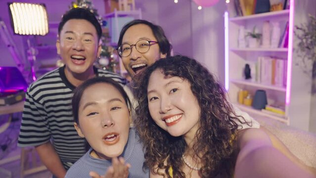 Group of Asian friends taking a selfie or video call in christmas party together