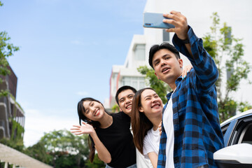 Group of happy young Asian students selfies and videos with smartphones together for vlog and social media on summer vacation. Concept of tourism and travel and road trip, friendship lifestyle.