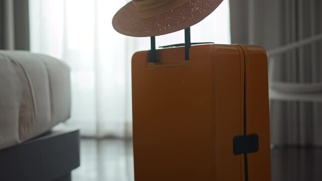 Suitcase or luggage bag with hat in a modern hotel room - relaxing time, holidays, weekend and traveling concept.
