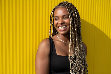 smiling beautiful young woman with a long braids posing on a yellow background