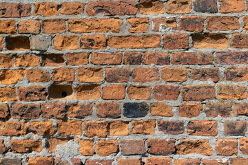 antique wall made of broken and cracked red bricks