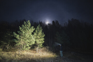 Night scene.  A man with a headlamp in a dark forest.  Photo with weak lighting.