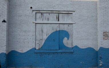 Close-up of a window with its shutter with a blue ocean wave painting