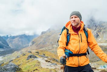 Fototapeta premium Portrait of caucasian man with backpack and trekking poles in Makalu Barun Park route near Khare. Mera peak climbing acclimatization active walk. Backpacker enjoying valley view. Active people concept