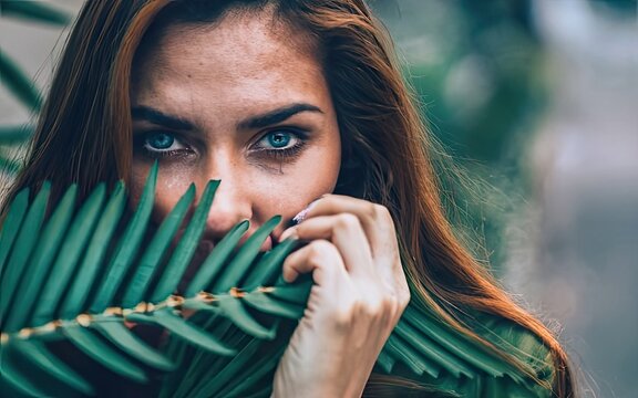 Blue Eyed Woman Hiding Behind Plant Leaves