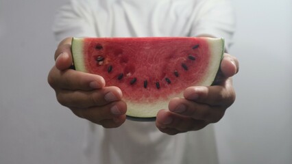 Sliced watermelon in hand isolated white. Red, white, green, and black color. Copy space.
