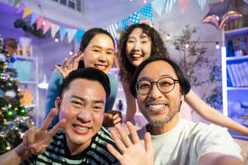 Group of Asian friends taking a selfie or video call in christmas party together