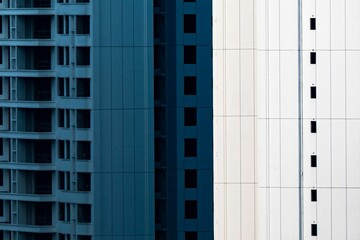 two tall buildings that are blue and white in color with square windows