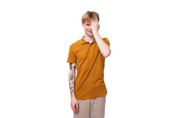 young handsome red-haired man with a haircut and a tattoo on his arm against the background of copy space