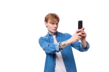 portrait of a caucasian red-haired guy in a denim blue shirt taking a selfie on the phone