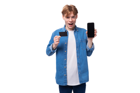 a young friendly man with red hair in a blue shirt and a white t-shirt shows the screen of a mobile phone and a credit card - Powered by Adobe