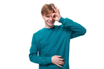 young caucasian student guy with red hair dressed in a blue sweater on a white background with copy space