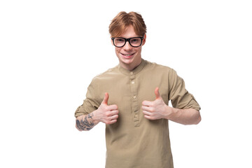 a young successful red-haired caucasian guy dressed in a khaki short-sleeve shirt looks at the...