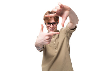 young handsome red-haired man in glasses and a shirt gesticulates and shows a frame on a white background