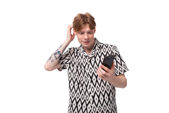 young surprised caucasian man with reddish golden hair in a black and white summer shirt is trying to remember something holding the phone in his hand