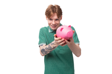 a young red-haired caucasian guy in a green t-shirt is about to empty his piggy bank