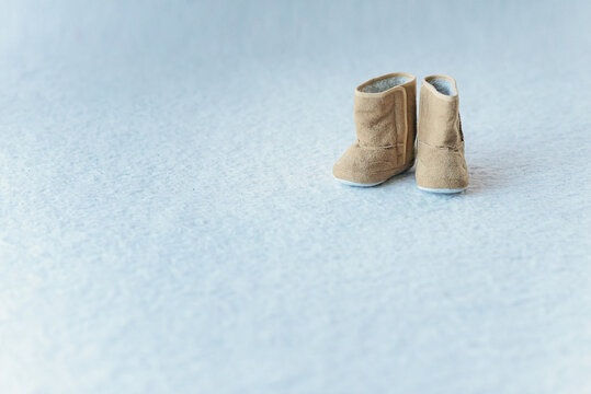 Pair of brown soft winter shoes on white background. Brown suede leather warm child boots with white fluffy fur. Free copy space.