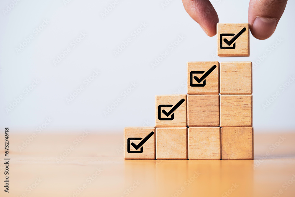Poster Hand stacking wooden block cube with correct tick sign symbol for project accept and document approve concept.