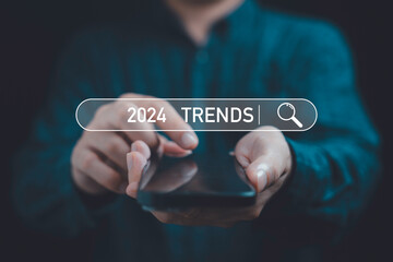 Businessman using smartphone with 2024 trends searching bar for marketing monitor and business...